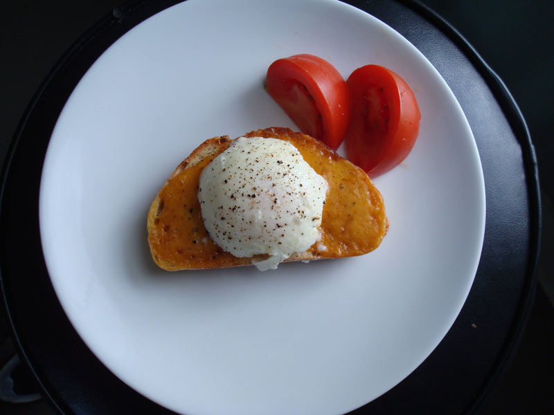 Poached egg on cheesy toast with truffle oil and tomatoes